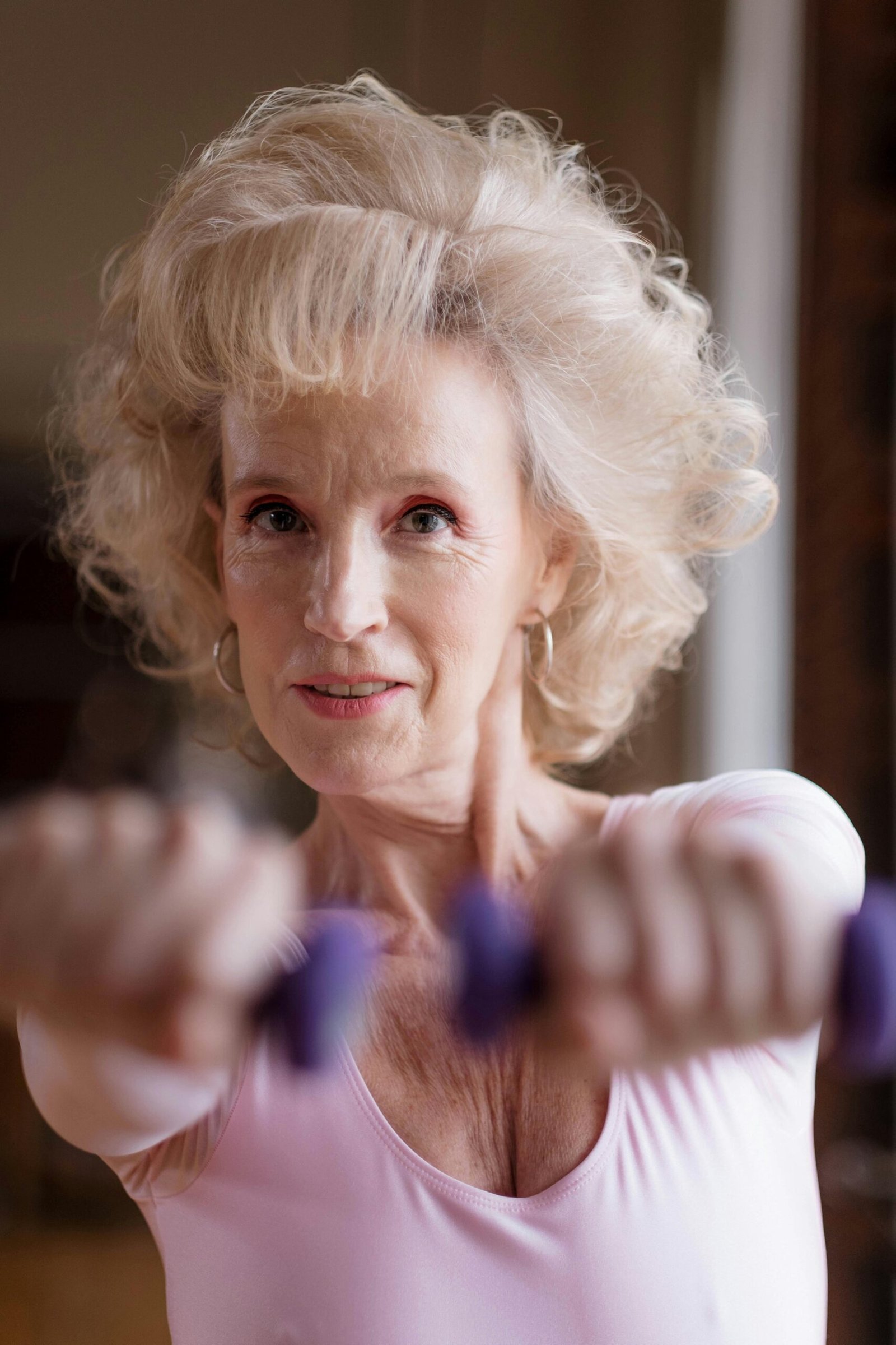 Elderly woman engaging in a fitness routine with dumbbells, promoting wellness and exercise at home.